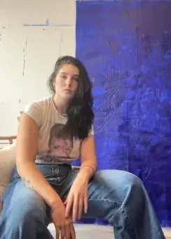 Ash seated beside a large cobalt blue painting