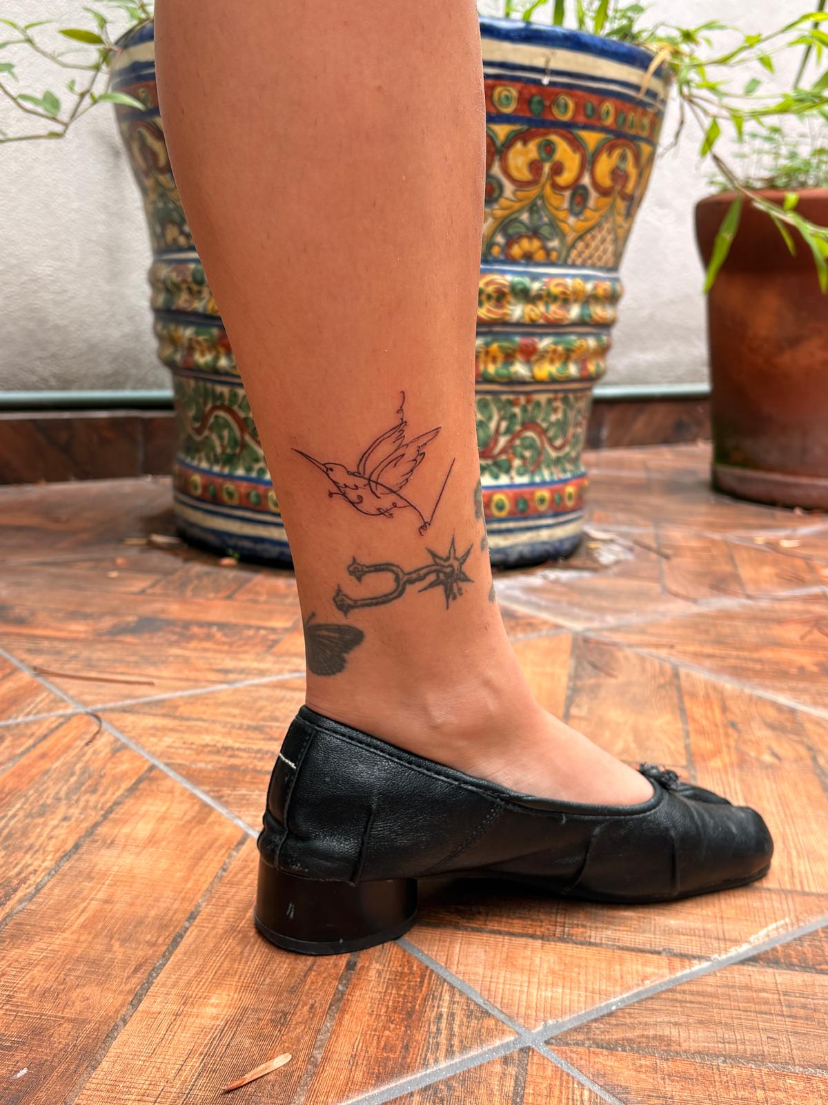 Small bird and star tattoo on an ankle