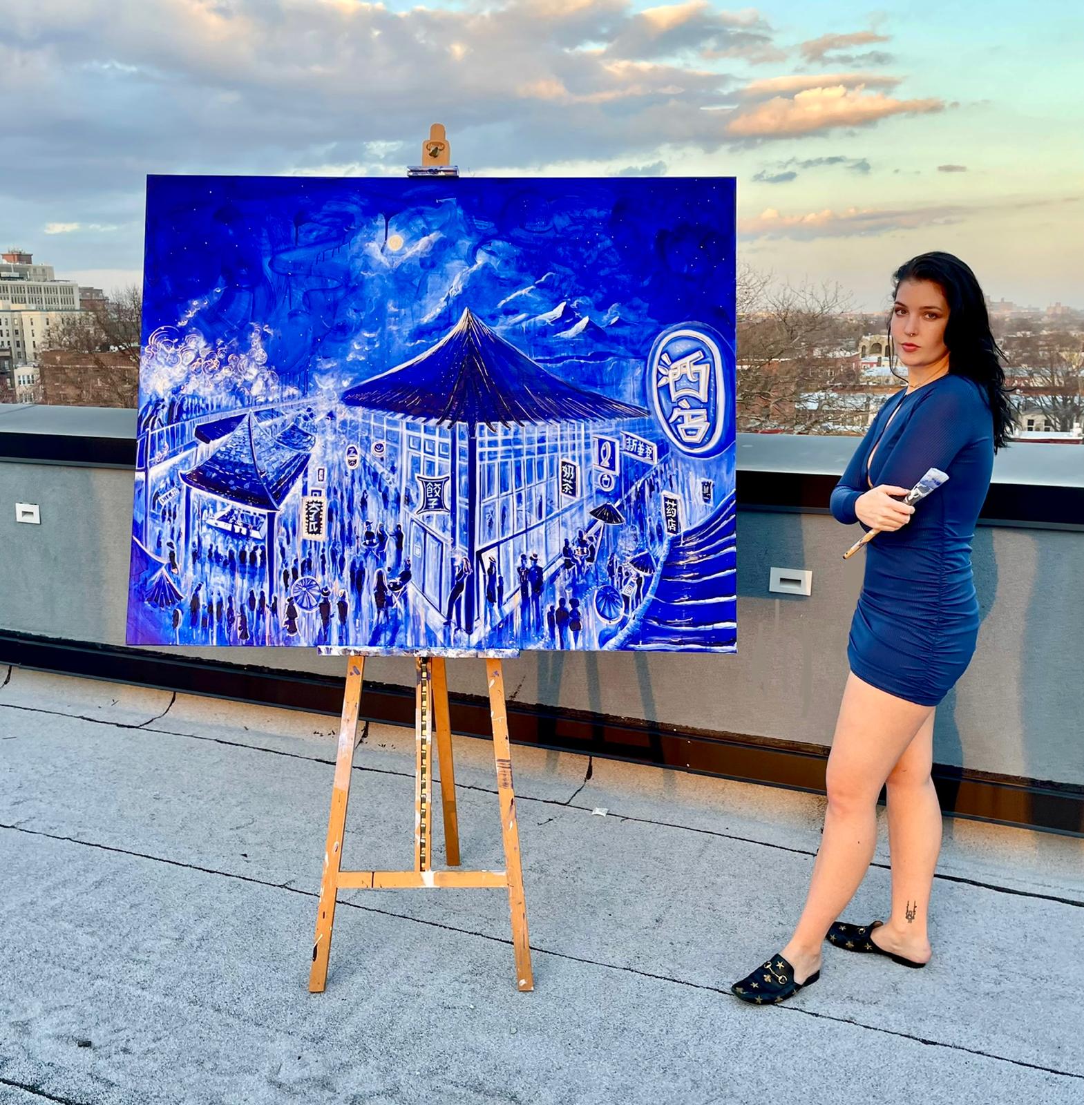 Ash Van Eyk on a rooftop beside her night market painting on an easel