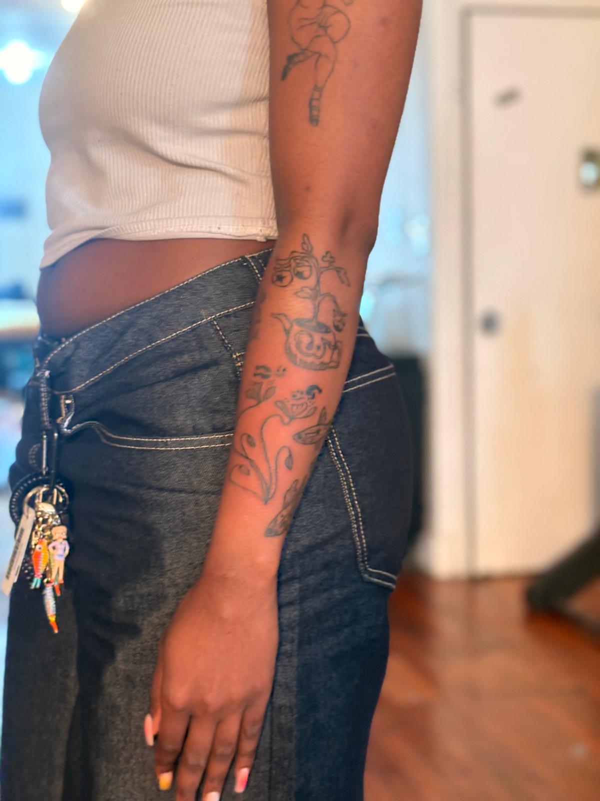 Forearm covered with fine-line sketch tattoos