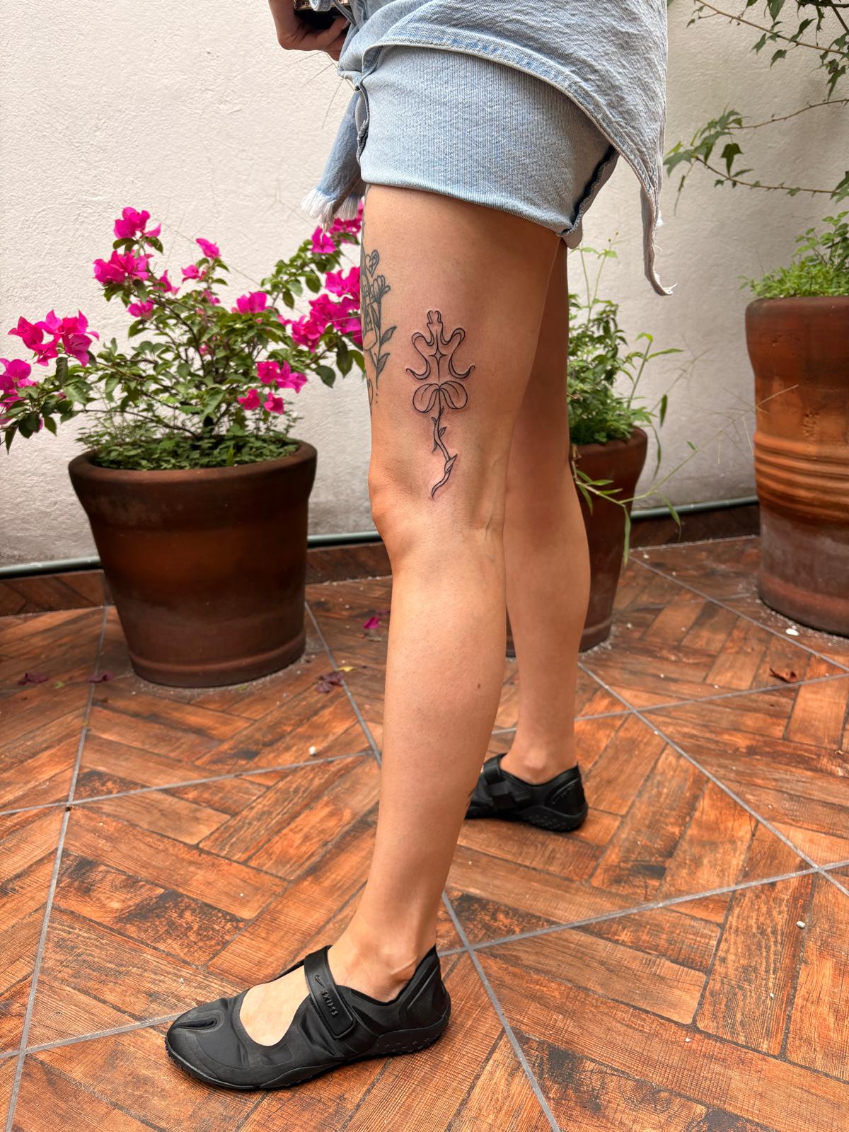 Botanical fine-line tattoo on the back of a thigh