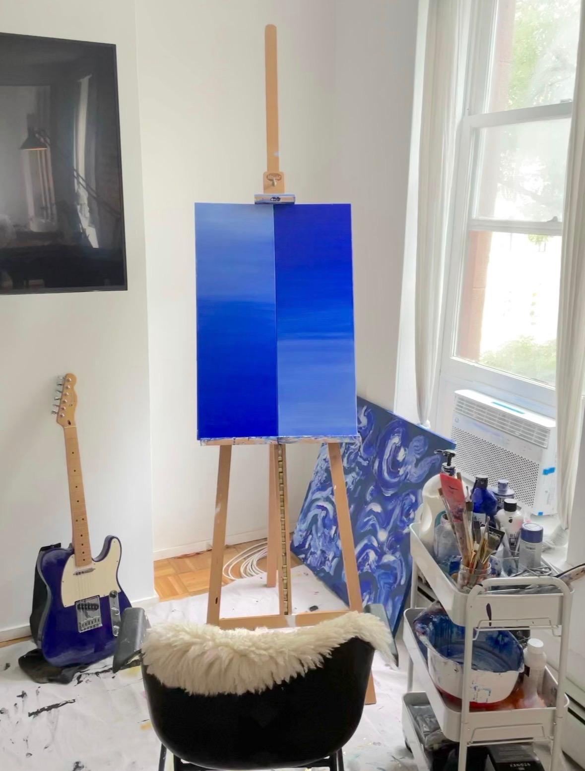 Studio with a blue gradient canvas on an easel and a blue guitar