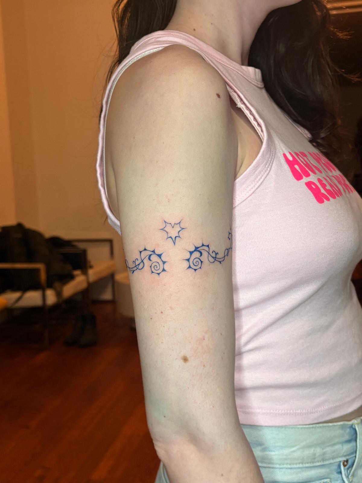 Armband of stars and spirals on an upper arm