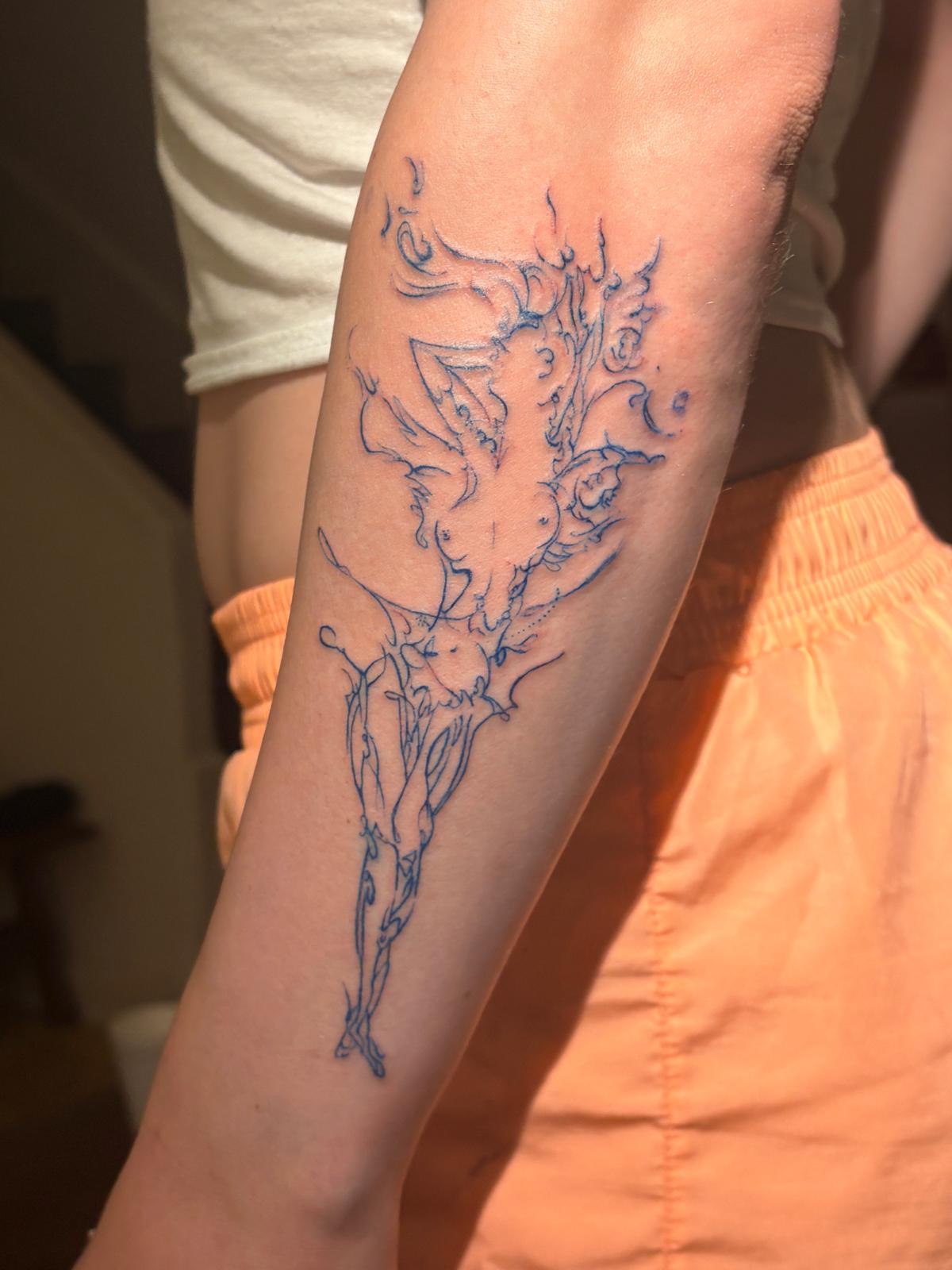Blue sketch-like surreal tattoo along a forearm