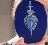 Oval blue painting with a white heart and sword