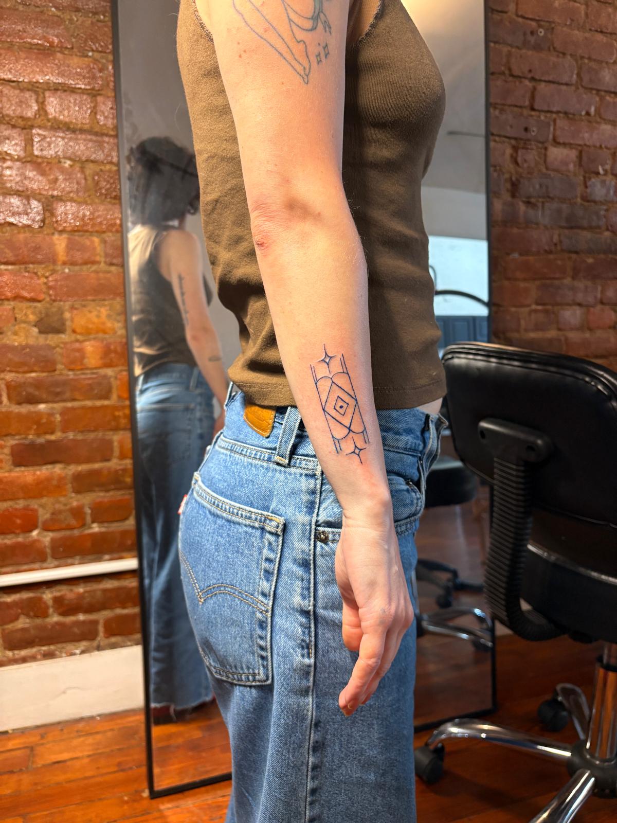 Small geometric star tattoo on a forearm