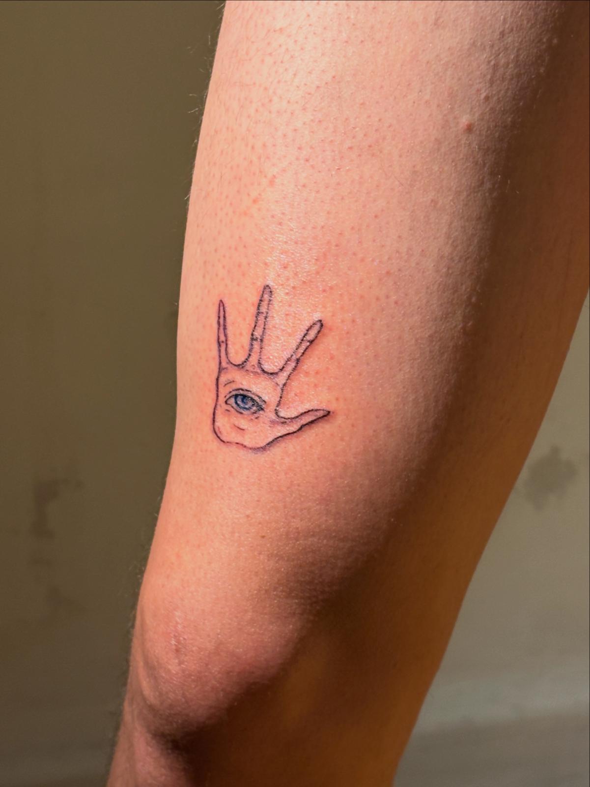 Hand with an eye in the palm tattooed on an arm