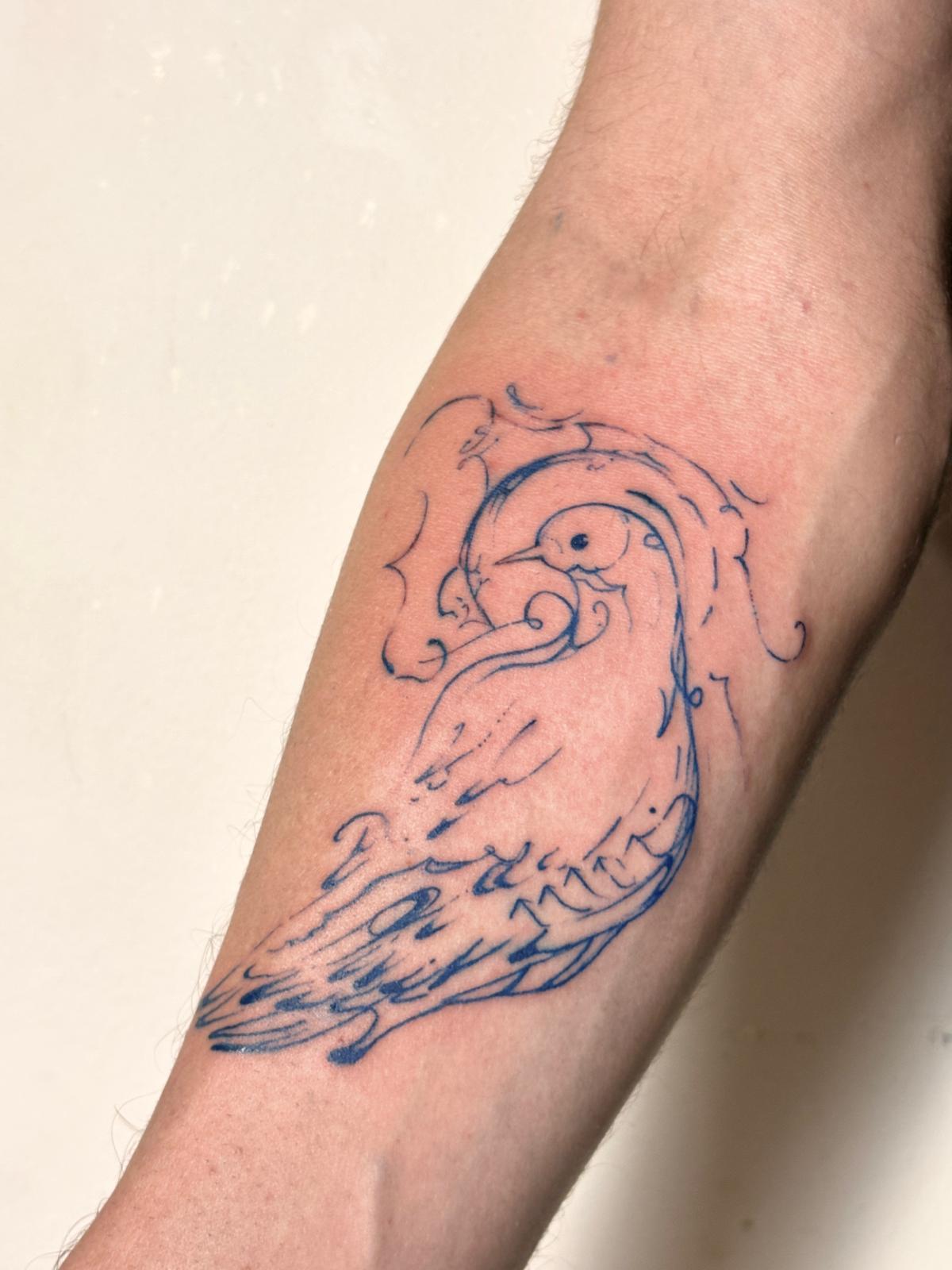Blue swirling bird tattoo on a forearm