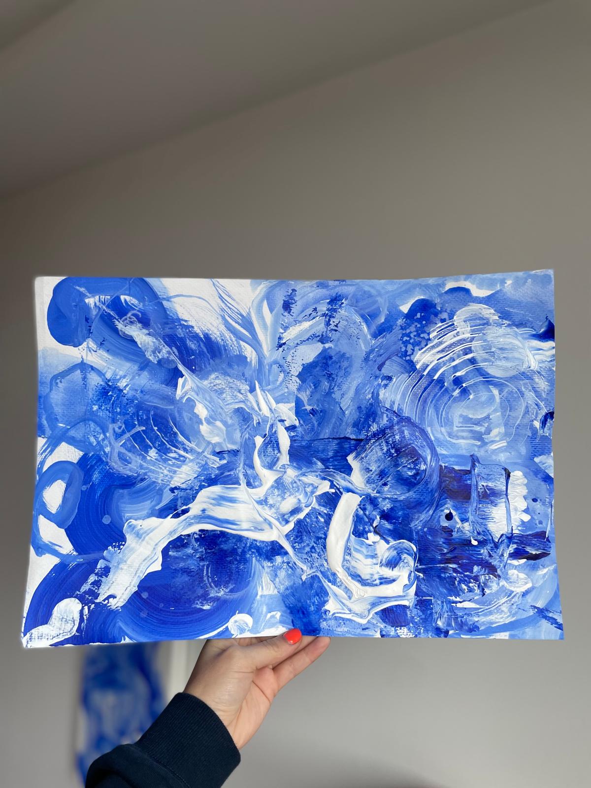 Hand holding a loose blue and white abstract painting